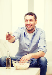 Image showing smiling man with tv remote control at home