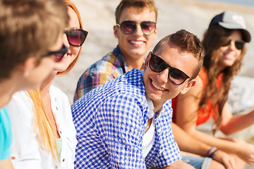 Image showing close up of smiling friends sitting on city street