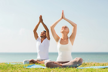 Image showing smiling couple making yoga exercises outdoors