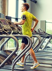 Image showing man with smartphone exercising on treadmill in gym