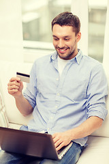 Image showing smiling man working with laptop and credit card