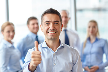 Image showing smiling business team showing thumbs up in office