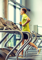 Image showing smiling man exercising on treadmill in gym