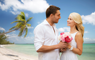 Image showing happy couple with flowers over beach background