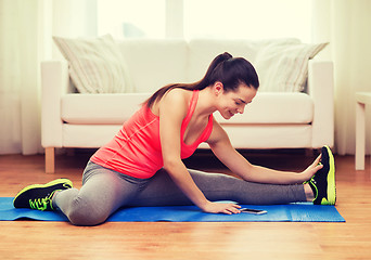 Image showing smiling teenage girl streching on floor at home