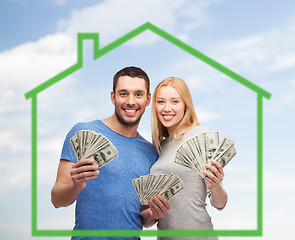 Image showing smiling couple holding money over green house