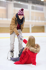Image showing man helping women to rise up on skating rink