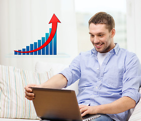 Image showing smiling man with laptop and growth chart at home