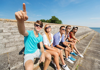 Image showing group of smiling friends sitting on city street