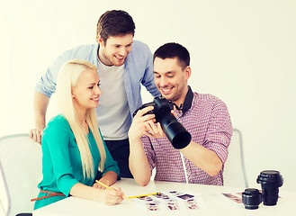 Image showing smiling team with photocamera working in office