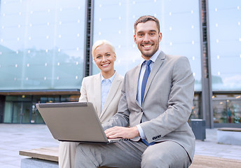 Image showing smiling businesspeople with laptop outdoors