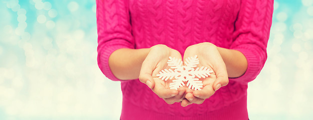 Image showing close up of woman in sweater holding snowflake