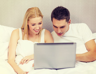 Image showing smiling couple in bed with laptop computer