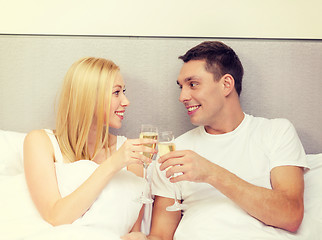 Image showing smiling couple with champagne glasses in bed