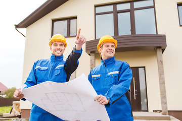 Image showing smiling builders with blueprint pointing finger