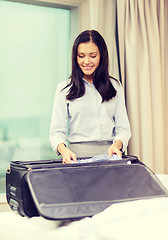 Image showing businesswoman packing things in suitcase