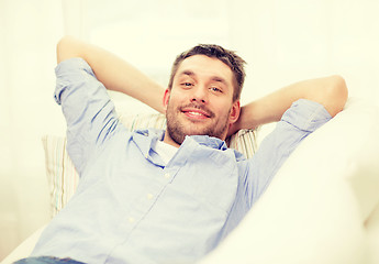 Image showing smiling man lying on sofa at home