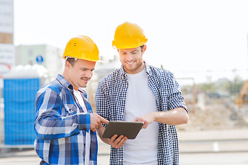 Image showing smiling builders in hardhats with tablet pc