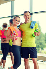 Image showing smiling couple with water bottles in gym