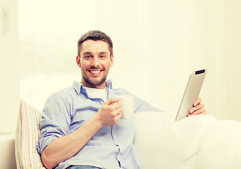 Image showing smiling man working with tablet pc at home