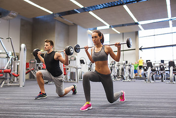 Image showing young man and woman training with barbell in gym