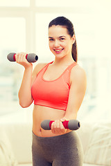 Image showing smiling teenage girl exercising with dumbbells