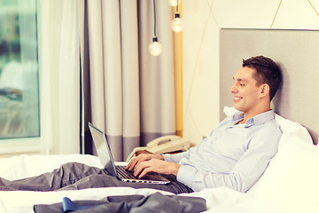 Image showing happy businesswoman with laptop in hotel room