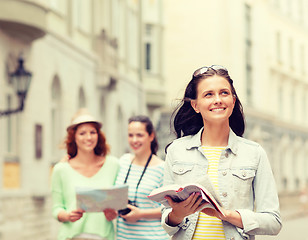 Image showing smiling teenage girls with city guides and camera