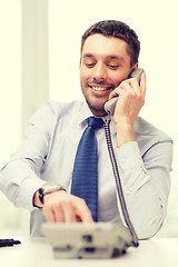 Image showing smiling businessman with telephone dialing number