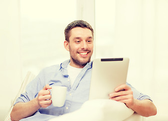 Image showing smiling man working with tablet pc at home