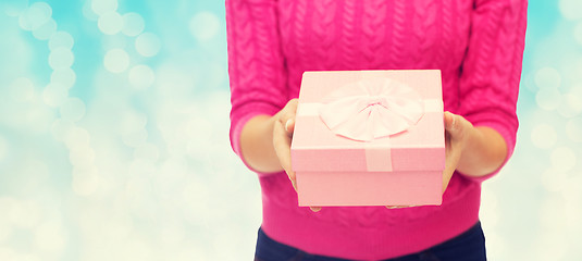 Image showing close up of woman in pink sweater holding gift box