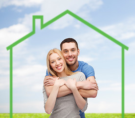 Image showing smiling couple hugging over green house