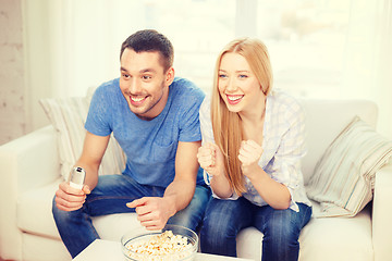 Image showing smiling couple with popcorn cheering sports team