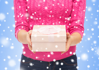 Image showing close up of woman in pink sweater holding gift box