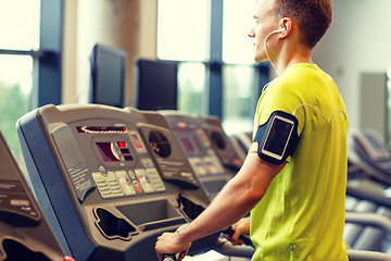 Image showing man with smartphone exercising on treadmill in gym