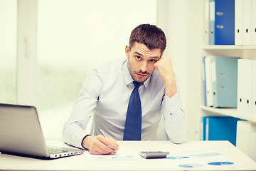 Image showing stressed businessman with laptop and documents