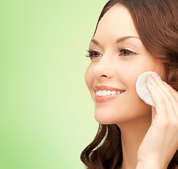 Image showing smiling woman cleaning face skin with cotton pad