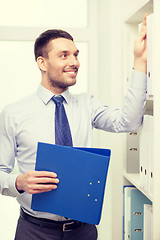 Image showing handsome businessman picking folder at office