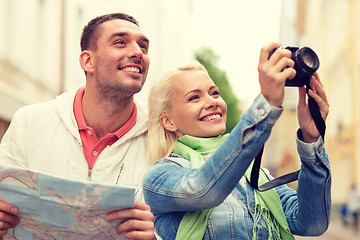 Image showing smiling couple with map and photocamera in city