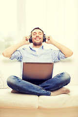 Image showing smiling man with laptop and headphones at home