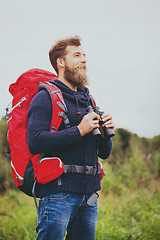 Image showing smiling man with backpack and binocular outdoors