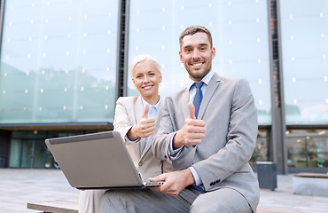 Image showing smiling businesspeople with laptop outdoors