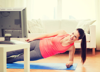 Image showing smiling teenage girl doing side plank at home