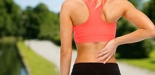 Image showing close up of sporty woman touching her back