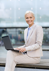 Image showing smiling businesswoman working with laptop outdoors