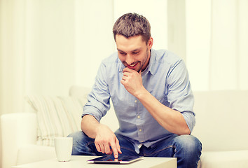 Image showing smiling man working with tablet pc at home