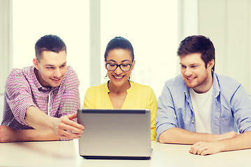 Image showing three smiling colleagues with laptop in office