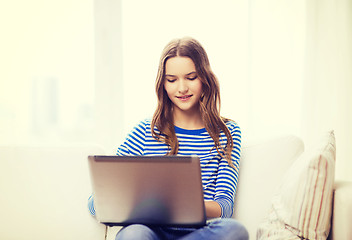 Image showing smiling teenage girl with laptop computer at home