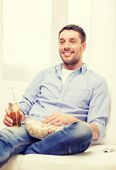 Image showing smiling man with beer and popcorn at home