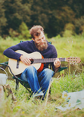 Image showing smiling man with guitar and dixie in camping